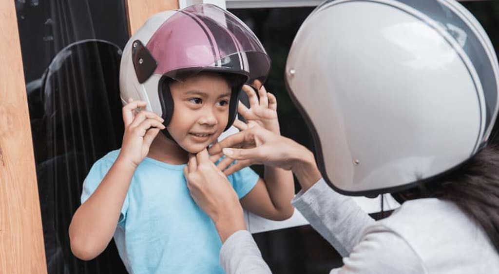 Permitirán viajar a niños en moto, pero con casco protector